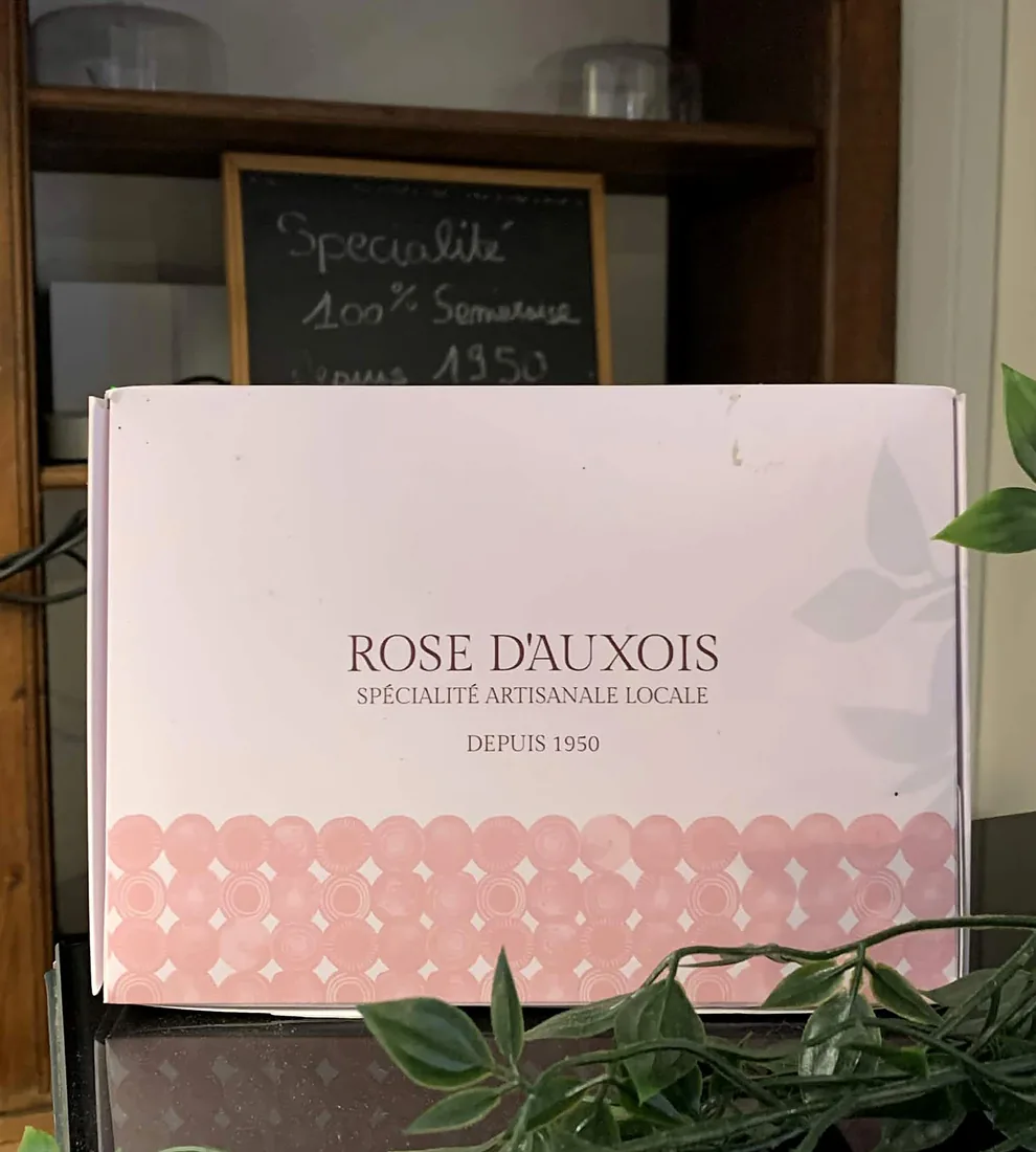 La boîte Rose d’Auxois devant l’ardoise « Spécialité 100&nbsp;% Semuroise depuis 1950 » à la pâtisserie